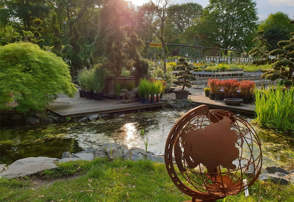 Dekorative Weltkugel vor dem Teich im Pflanzgarten